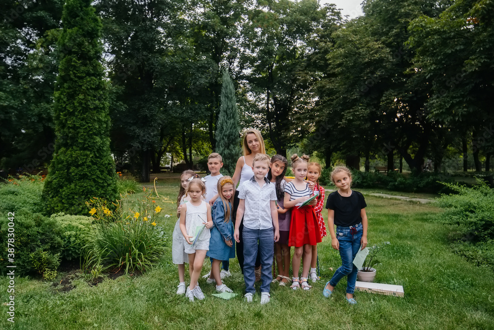 Obraz premium A teacher teaches a class of children in an outdoor Park. Back to school, learning during the pandemic
