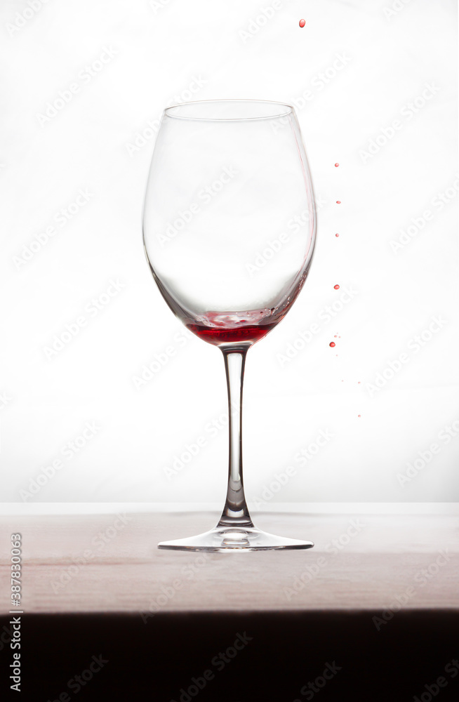 A glass of wine with a little bit of wine and a few drops of red on the outside A glass of wine with a little bit of wine and a few drops of red on the outside
