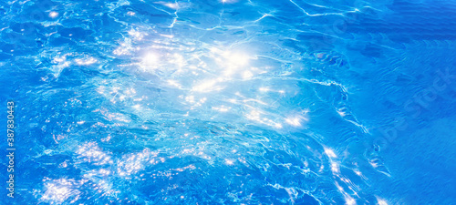 water in swimming pool background the surface of the water. texture, blue water, bright rays of the sun. web panorama banner with copy space.