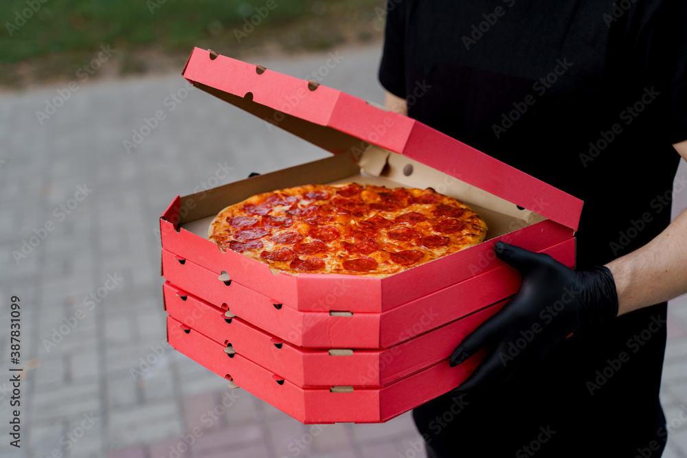 Safety pizza delivery from restaurant. Food courier in black medical ...