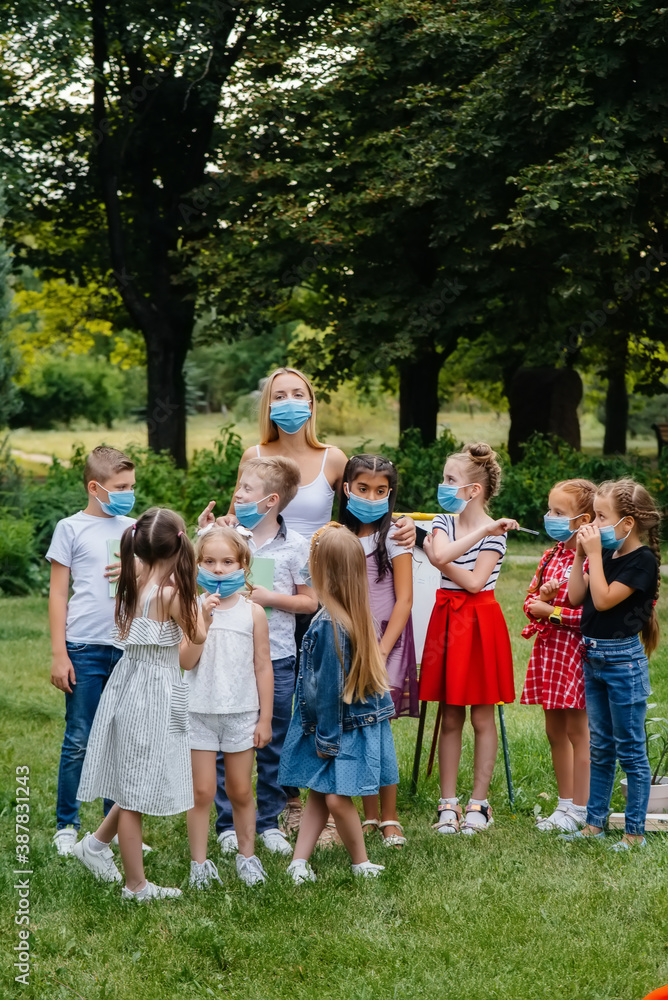Obraz premium A class of masked school children is engaged in outdoor training during the epidemic. Back to school, learning during the pandemic