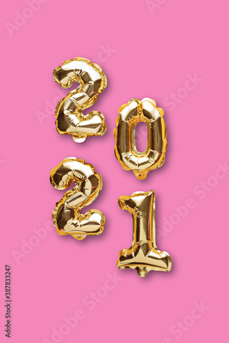 vertical gold foil balloons numbers 2021 on pink background, christmas composition, top view