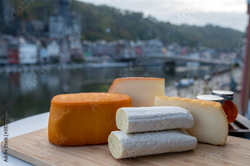 Cheese collection, Belgian abbey cheeses made with brown trappist beer and fine herbs and view on Maas river in Dinant, Wallonia, Belgium photo