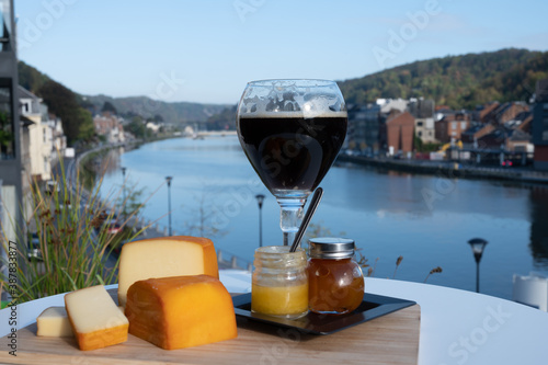 Glass of Belgian abbey beer and tasting of cheeses made with trappist beer and fine herbs with view on Maas river in Dinant, Wallonia, Belgium photo