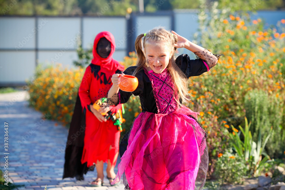 Fototapeta premium A girl dressed as a witch runs away from a boy dressed as an executioner.