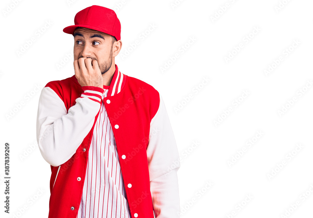 Young handsome man wearing baseball jacket and cap looking stressed and nervous with hands on mouth biting nails. anxiety problem. Young handsome man wearing baseball jacket and cap looking stressed and nervous with hands on mouth biting nails. anxiety problem.