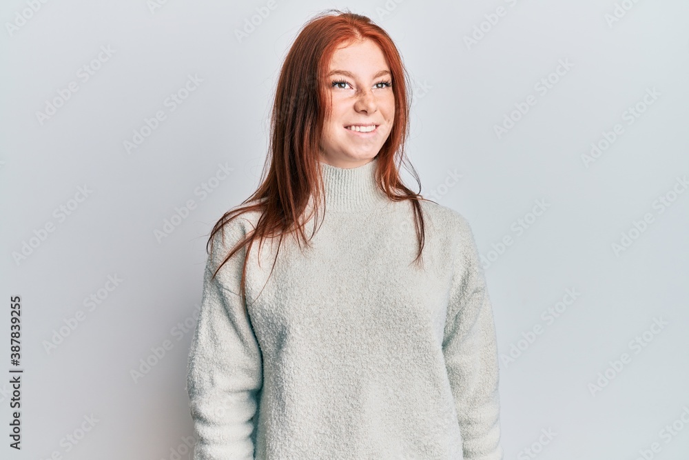 Obraz premium Young red head girl wearing casual winter sweater looking to side, relax profile pose with natural face and confident smile.