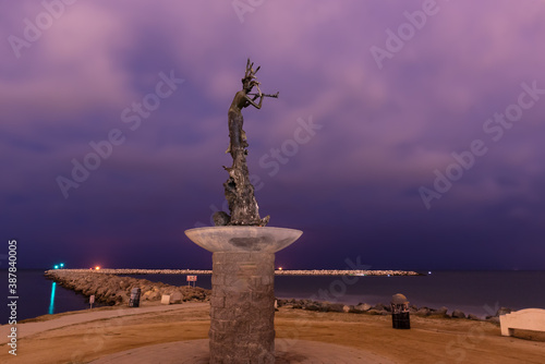 Mermaid statue beacon stands tall over harbor mouth rock jetty as ominious stormy clouds cirlce the sky overhead. photo