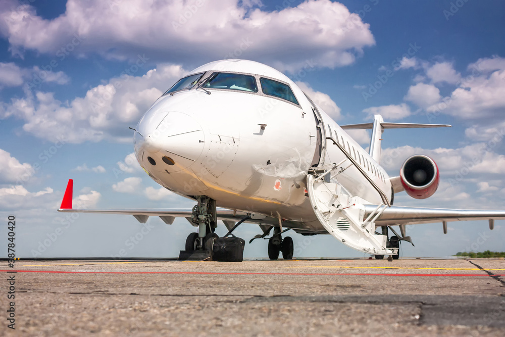 Close-up white corporate business jet with a lowered gangway door on the airport apron Close-up white corporate business jet with a lowered gangway door on the airport apron