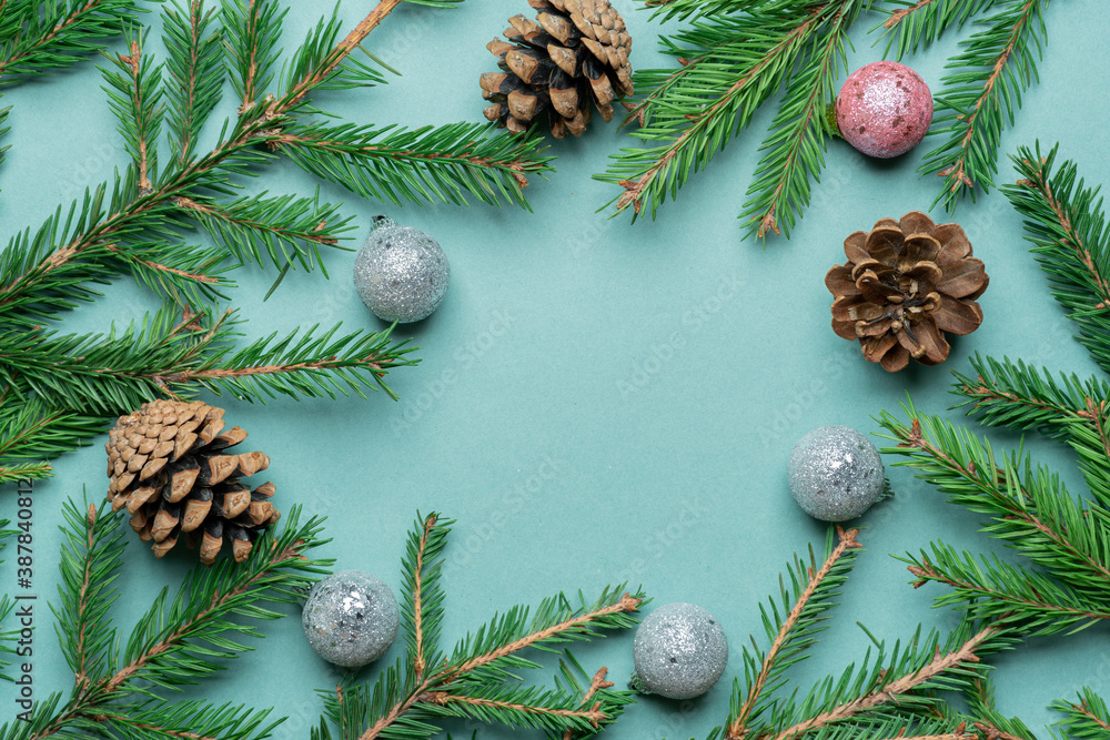 Fir, spruce branches, pine cones and Christmas tree toys on green background with copy space