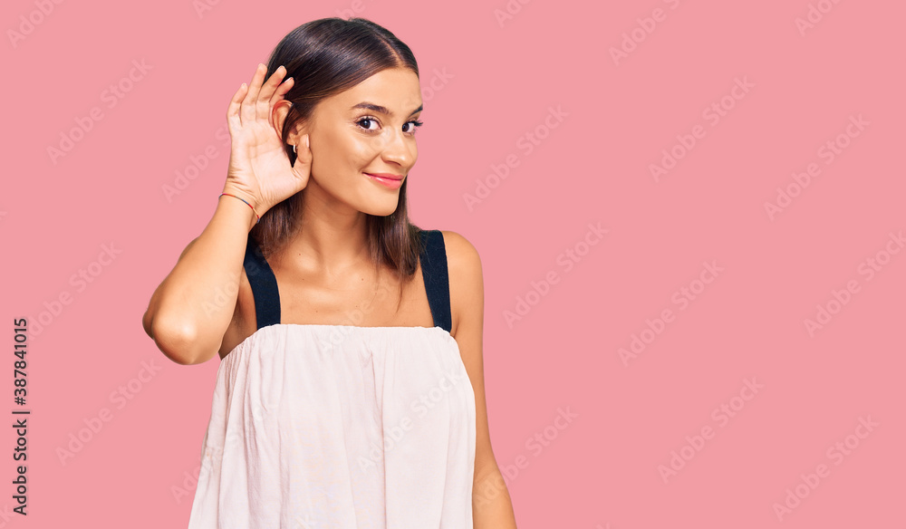 Fototapeta premium Young hispanic woman wearing casual clothes smiling with hand over ear listening an hearing to rumor or gossip. deafness concept.