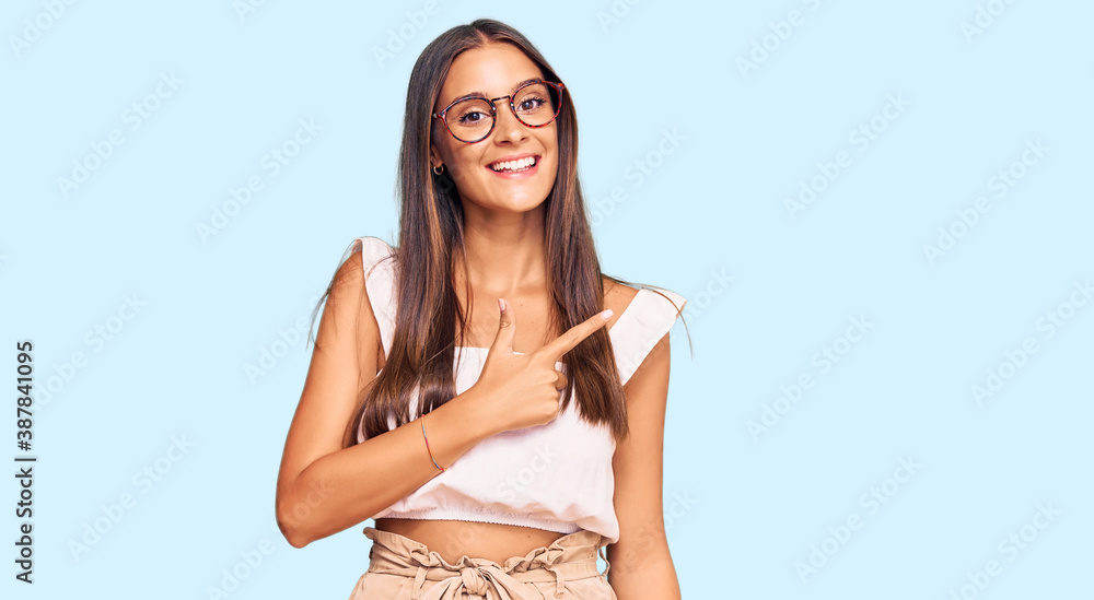 Fototapeta premium Young hispanic woman wearing casual clothes and glasses cheerful with a smile on face pointing with hand and finger up to the side with happy and natural expression