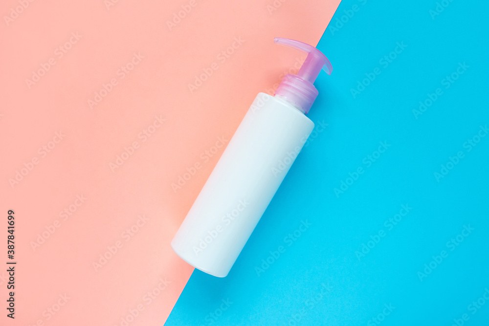 Bottle for liquid, cream, gel, lotion. Сosmetic bottle on blue and rose background. SPA cosmetic product branding mockup.
Flat lay minimalist style.