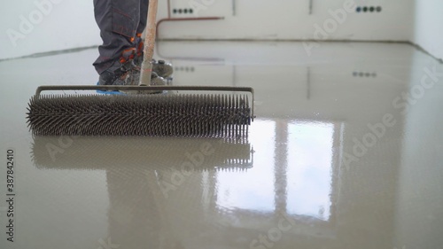 A contractor painter will paint the garage floor to speed up the sale of your home. Floor screed filling, repair and finishing. Fill in the low spots with self-leveling compound for a fine leveling.  photo