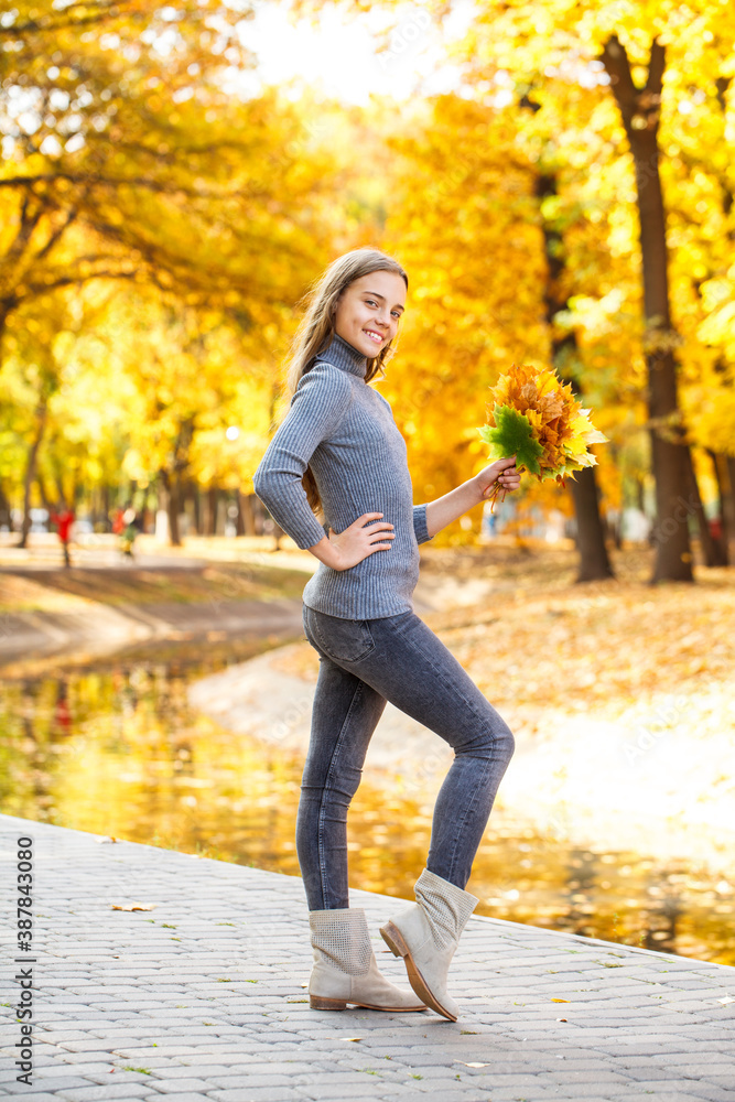 Full length portrait of a young beautiful girl posing in an autumn park Full length portrait of a young beautiful girl posing in an autumn park