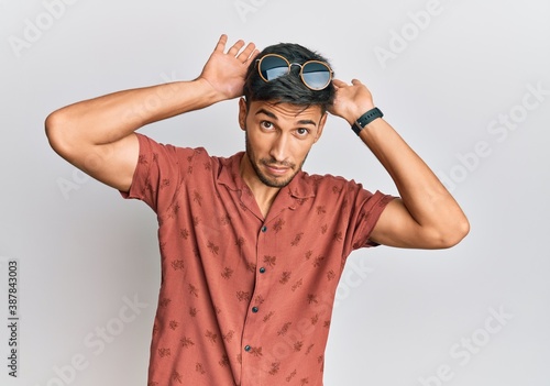 Young handsome man wearing casual summer clothes doing bunny ears gesture with hands palms looking cynical and skeptical. easter rabbit concept.