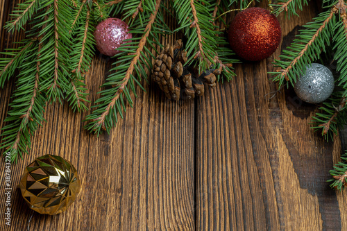 Fir, spruce branches, cones and Christmas tree toys on brown wooden background