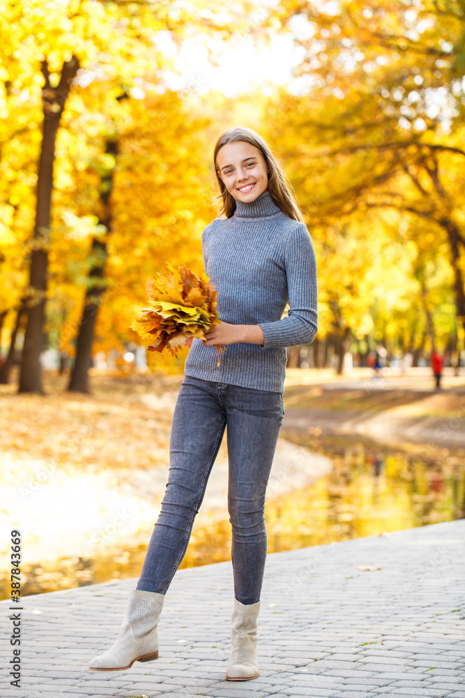 Full length portrait of a young beautiful girl posing in an autumn park Full length portrait of a young beautiful girl posing in an autumn park