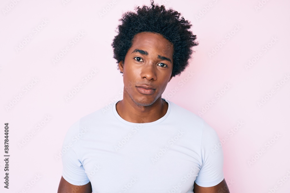 Handsome african american man with afro hair wearing casual clothes with serious expression on face. simple and natural looking at the camera. Handsome african american man with afro hair wearing casual clothes with serious expression on face. simple and natural looking at the camera.