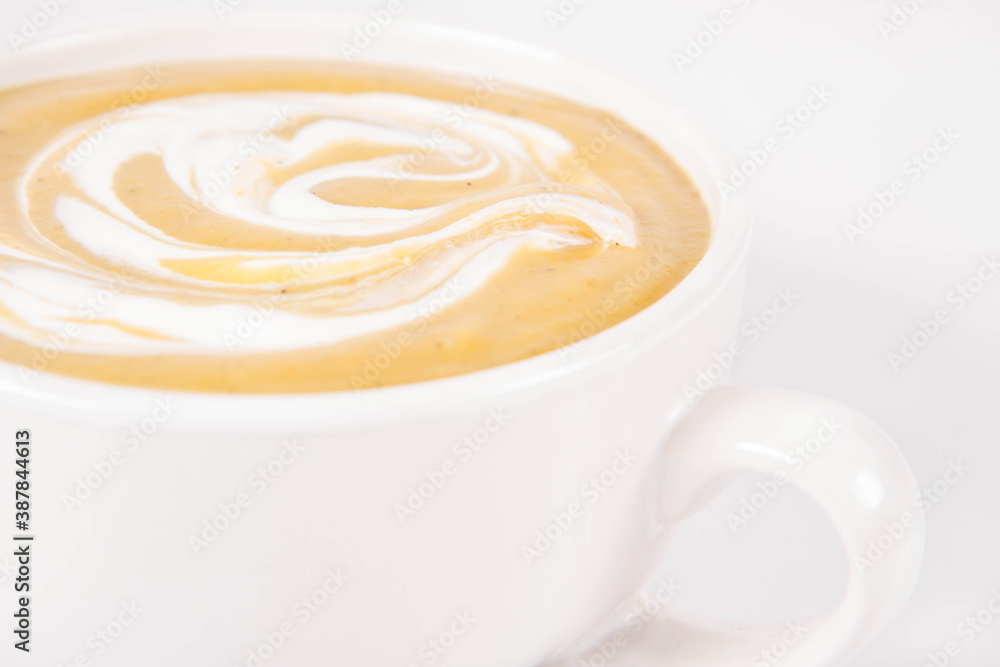 Pumpkin soup decorated with cream in a bowl on a white background Pumpkin soup decorated with cream in a bowl on a white background