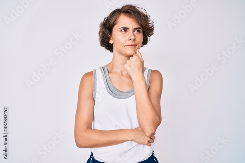Young hispanic woman wearing sportswear serious face thinking about question with hand on chin, thoughtful about confusing idea