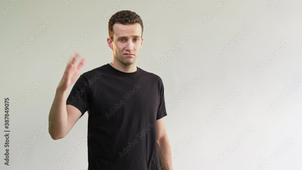 Dislike gesture. Disgusted man. Bad idea. Refusal sign. Skeptic annoyed guy in black t-shirt rejecting offer with thumb down go away no signal isolated on light neutral empty space background. Dislike gesture. Disgusted man. Bad idea. Refusal sign. Skeptic annoyed guy in black t-shirt rejecting offer with thumb down go away no signal isolated on light neutral empty space background.