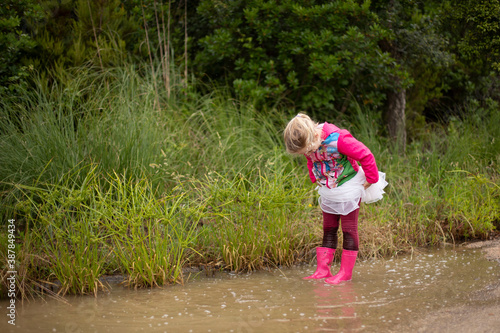 little girl in white tutu skirt splashing in the puddle © Eugenia
