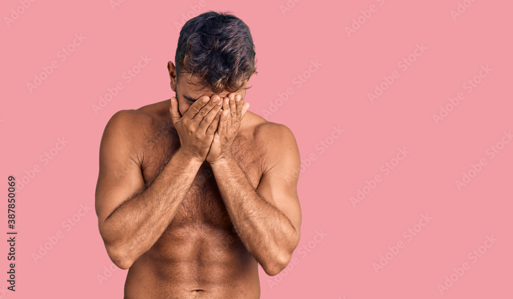 Fototapeta premium Young hispanic man wearing swimwear shirtless with sad expression covering face with hands while crying. depression concept.