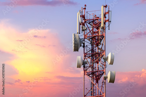 Telecommunication tower with antennas against beautiful colorful sky at sunset or dawn with pink clouds background.