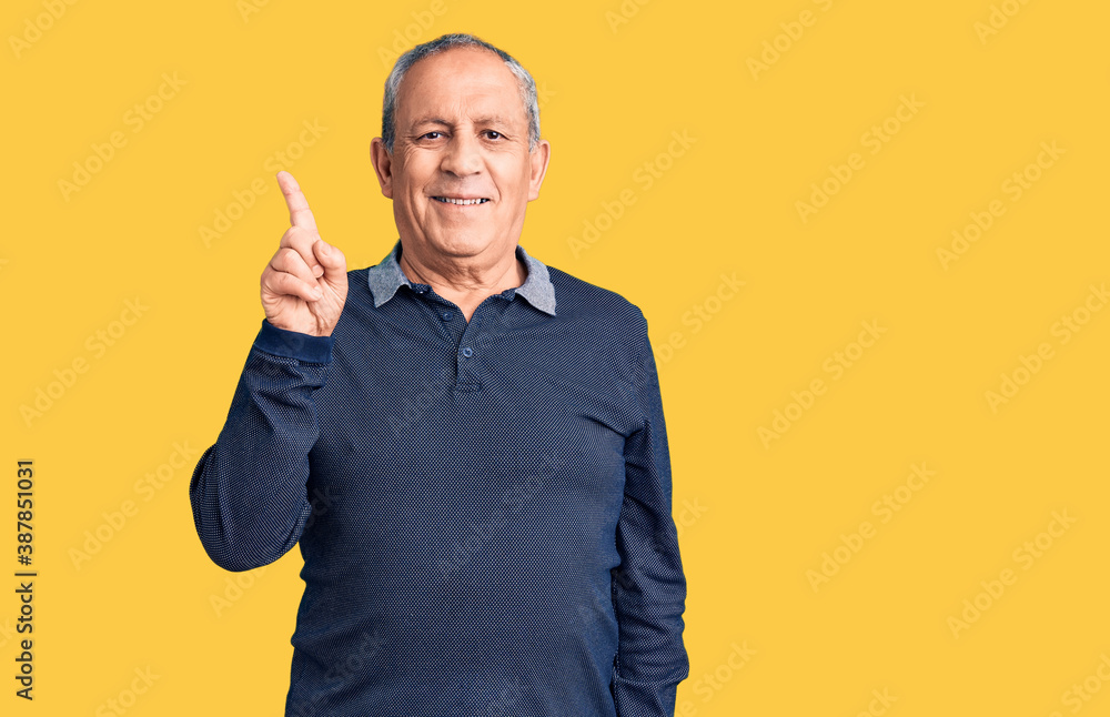Senior handsome man wearing casual polo with a big smile on face, pointing with hand and finger to the side looking at the camera. Senior handsome man wearing casual polo with a big smile on face, pointing with hand and finger to the side looking at the camera.