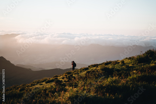 man is taking pictures during the sunset on top of a mountain