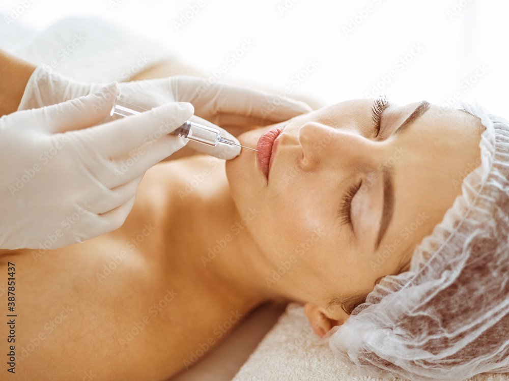 © rogerphoto - Beautician doing beauty procedure with syringe to face of young brunette woman. Cosmetic medicine and surgery, beauty injections