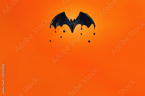 black bat with red eyes on an orange background.