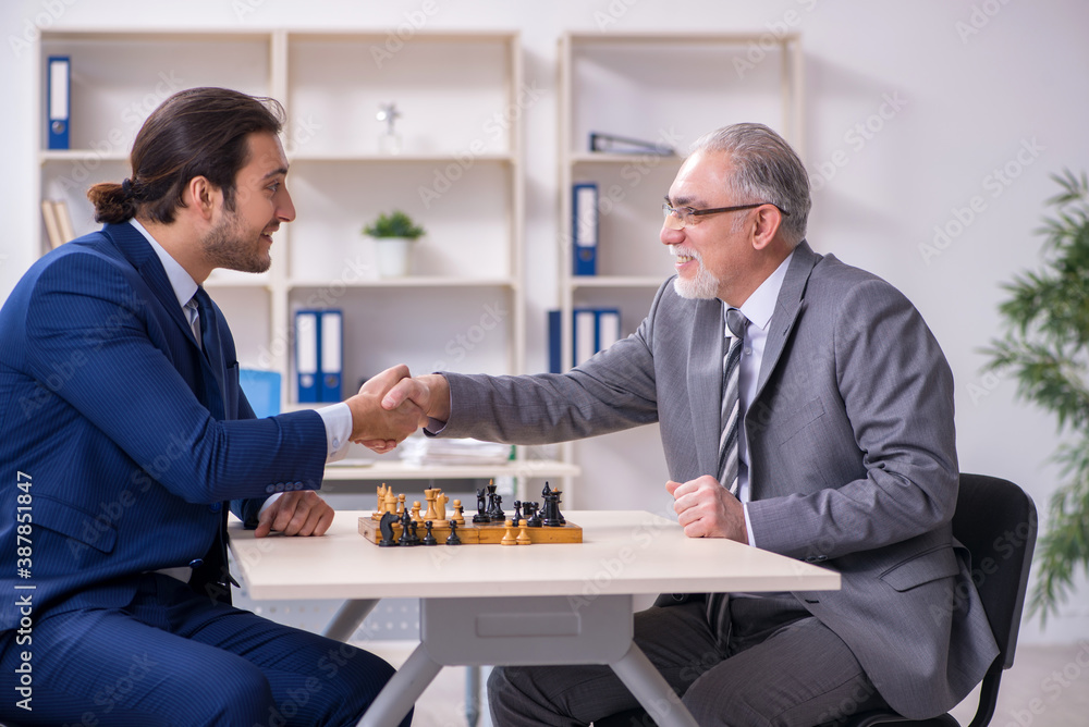 Two businessmen playing chess in the office Two businessmen playing chess in the office