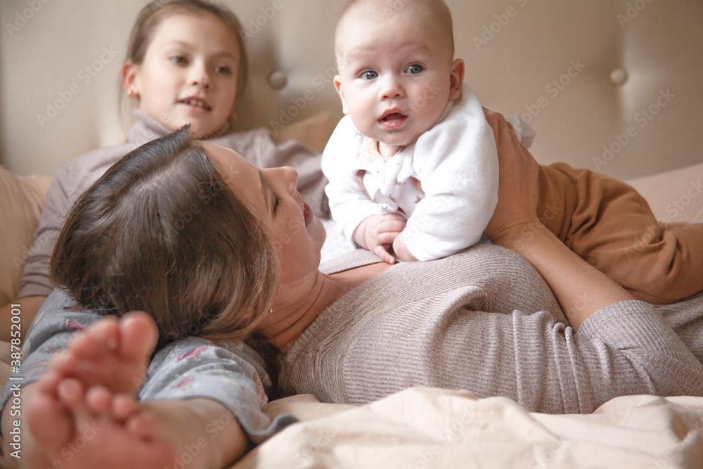 Mother holding infant baby, take care of her 3 months old child at home bedroom . Happy mom carying of her newborn son . Mother and elder sister kissing the boy Mother holding infant baby, take care of her 3 months old child at home bedroom . Happy mom carying of her newborn son . Mother and elder sister kissing the boy