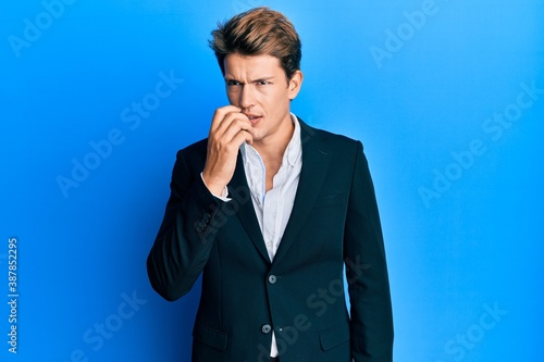 Handsome caucasian man wearing business suit and tie looking stressed and nervous with hands on mouth biting nails. anxiety problem.