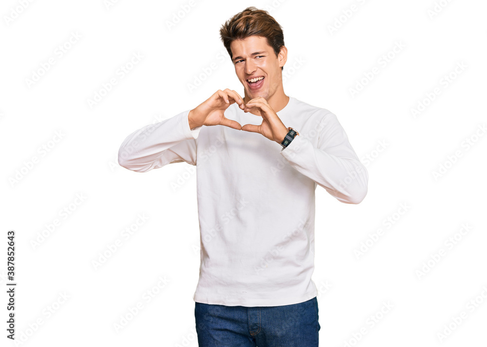 Handsome caucasian man wearing casual white sweater smiling in love doing heart symbol shape with hands. romantic concept.