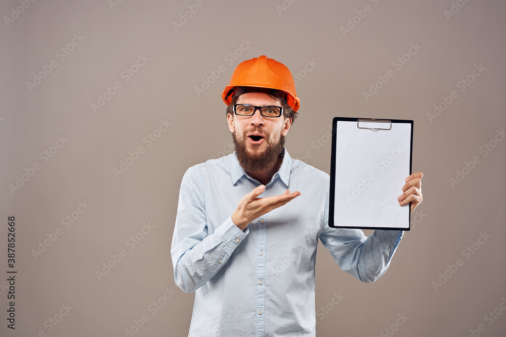 A man in a shirt with an orange hard hat engineer work documents rendering services A man in a shirt with an orange hard hat engineer work documents rendering services