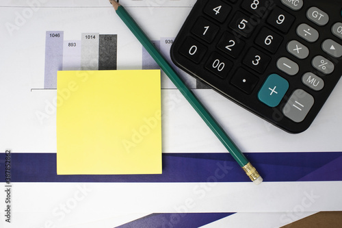 on business documents in the form of a graph, there is a yellow sheet for notes a calculator and a pencil. Business concept