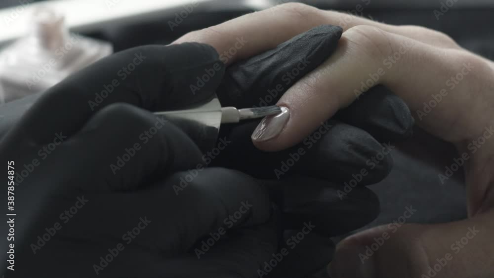 The master in black latex protective gloves dips a brush in a tube with a beige varnish. Beauty Salon, Manicure. High quality 4k footage The master in black latex protective gloves dips a brush in a tube with a beige varnish. Beauty Salon, Manicure. High quality 4k footage