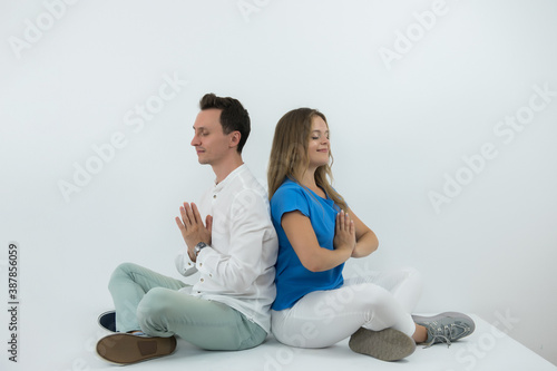 Calm couple meditating together at home, mindful peaceful man and woman practicing yoga sitting in lotus pose