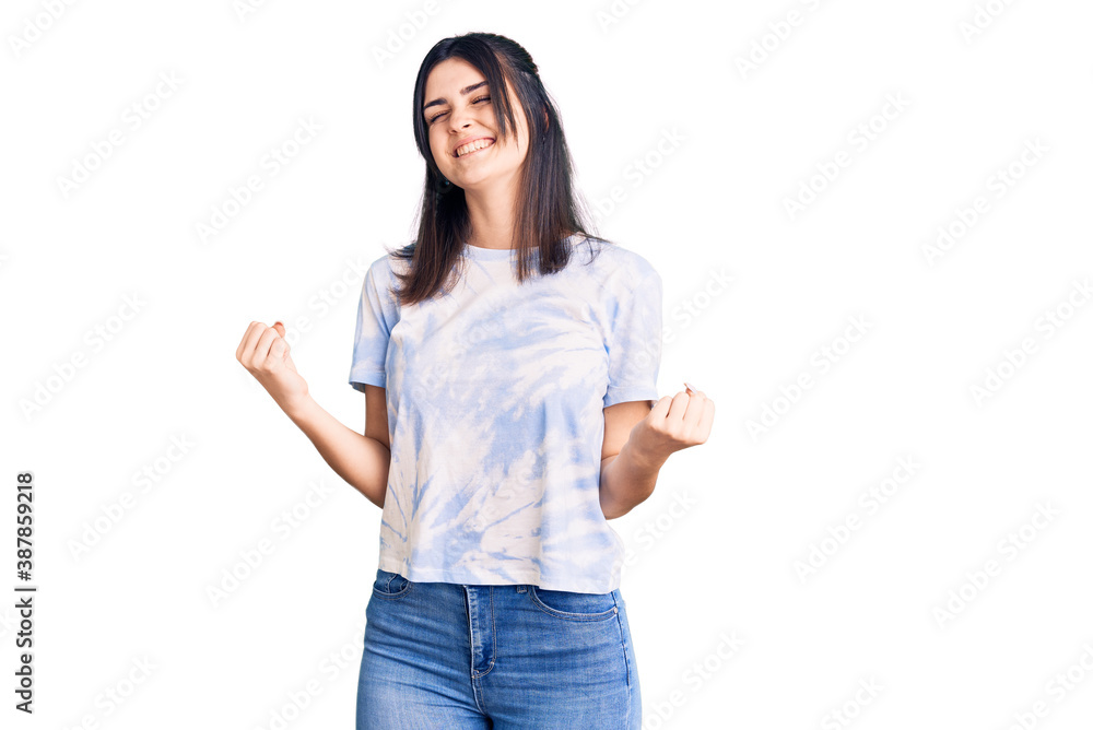 Young beautiful girl wearing casual t shirt very happy and excited doing winner gesture with arms raised, smiling and screaming for success. celebration concept. Young beautiful girl wearing casual t shirt very happy and excited doing winner gesture with arms raised, smiling and screaming for success. celebration concept.