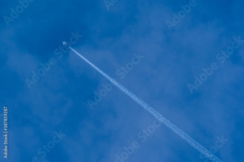 Minimalist Blue Sky with Jet going diagonally LR to UL with contrails