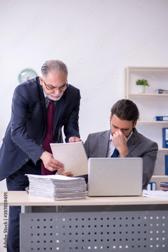 Old boss and his young assistant working in the office Old boss and his young assistant working in the office