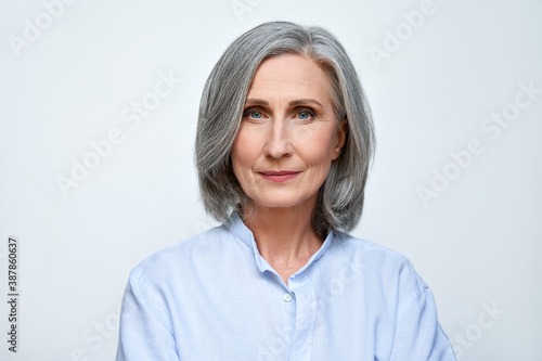Confident beautiful mature business woman standing isolated on white background. Older senior businesswoman, 60s grey haired lady professional looking at camera, close up face headshot portrait. photo