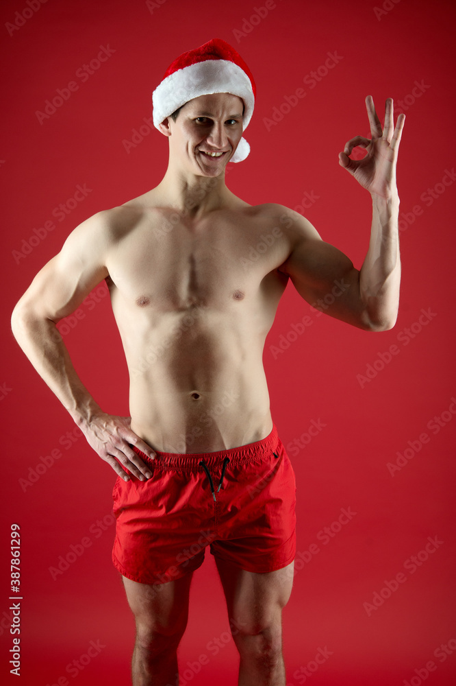 Happy Santa with muscular torso show approval OK hand sign red background, approved