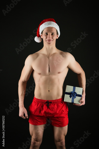 Happy athletic santa claus with six pack abs hold Christmas gift box holiday shopping, boxing day