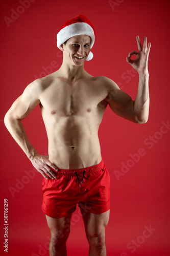 Happy Santa with muscular torso show approval OK hand sign red background, approved © be free
