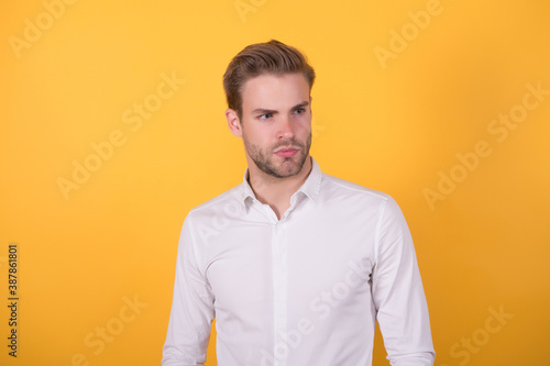 handsome guy with bristle wearing white shirt standing on orange background, business fashion