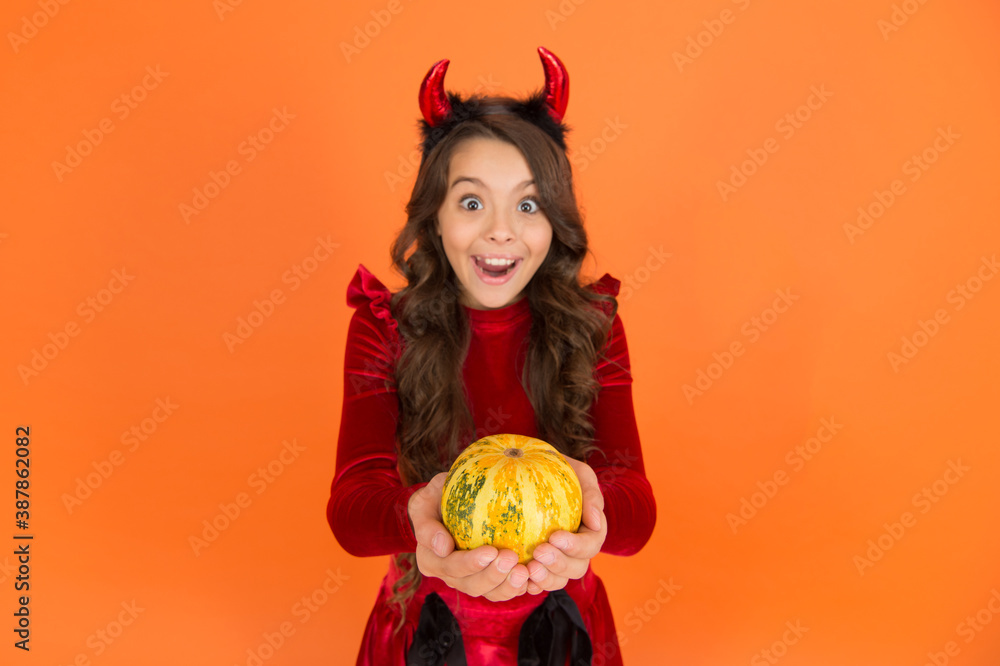 surprised halloween devil kid in imp horns hold pumpkin for jack o lantern, selective focus, happy halloween surprised halloween devil kid in imp horns hold pumpkin for jack o lantern, selective focus, happy halloween